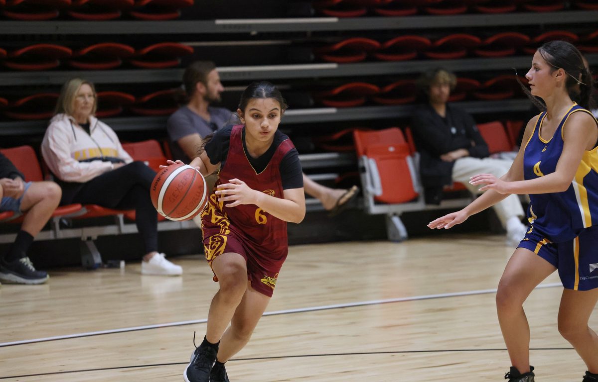 Rotorua player drives with the ball past a defender.