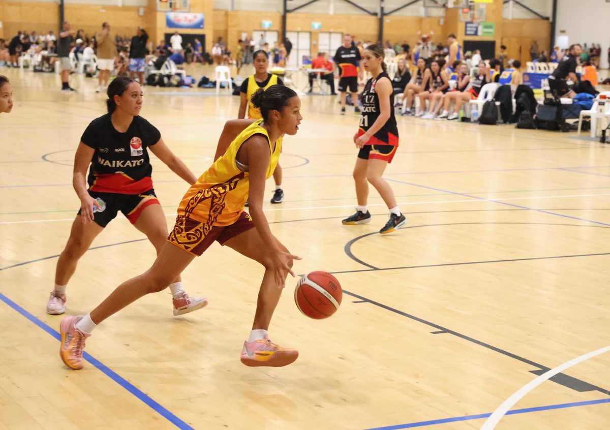Rotorua player in gold drives past a defender.