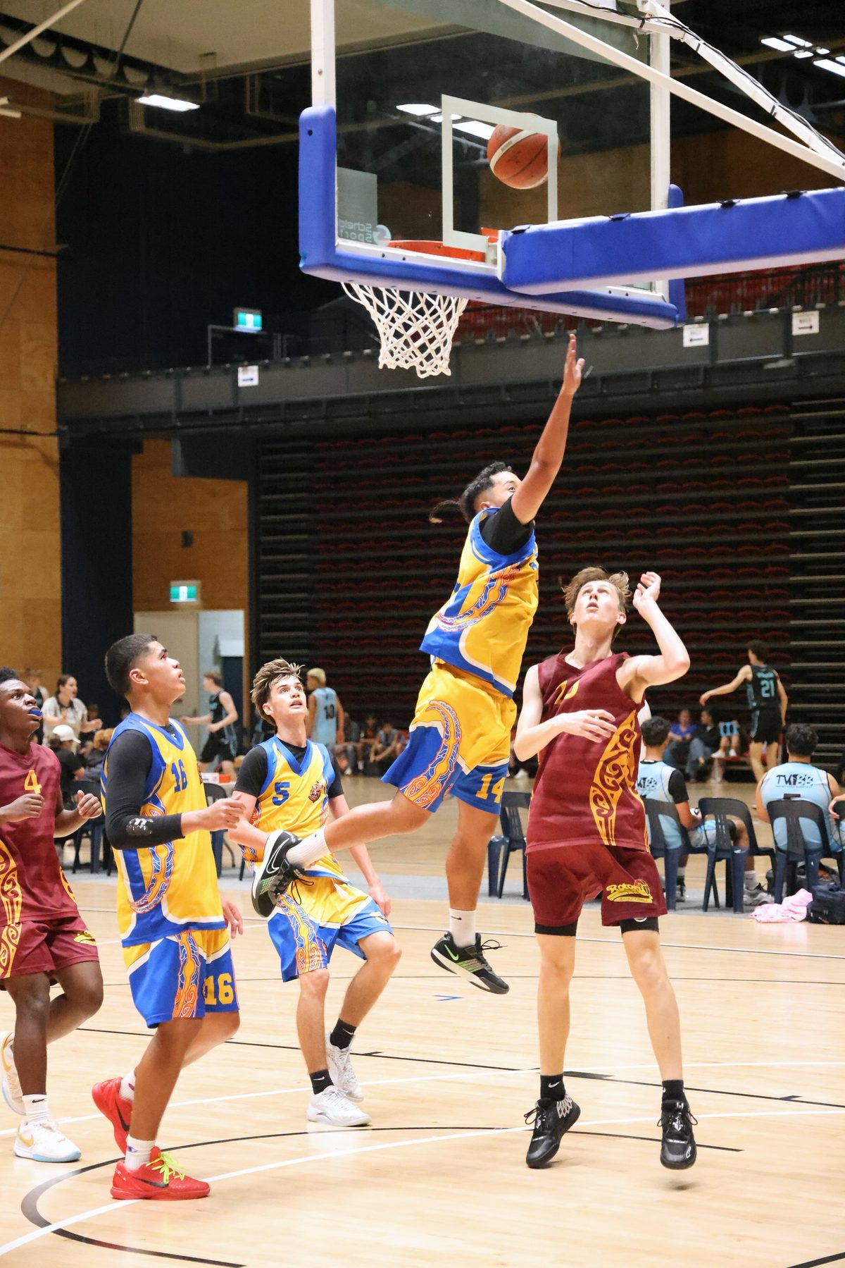 Players contest a layup beneath the basketball hoop.
