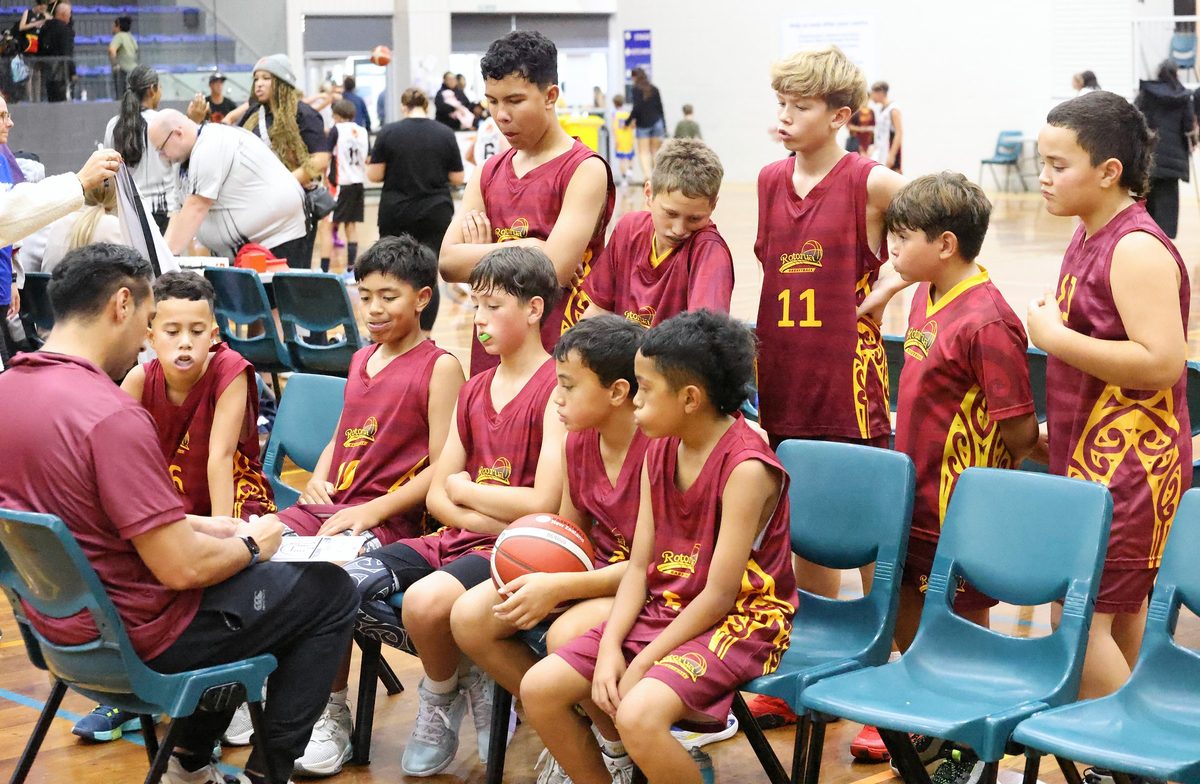 Junior Rotorua players gather around their coach and tactics board.