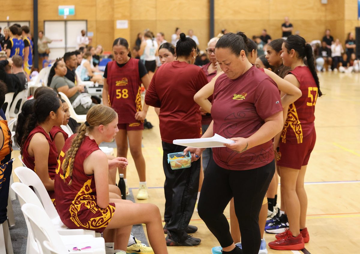 Rotorua team staff and players gather beside the bench.