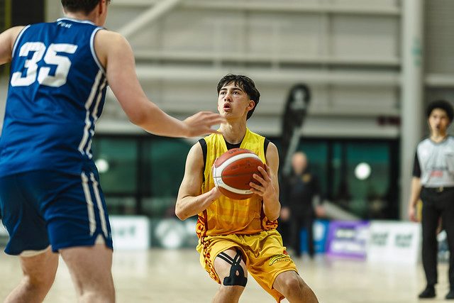 Rotorua player gathers the ball while facing a defender near the basket.