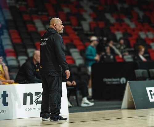 A coach watches the game from the sideline.