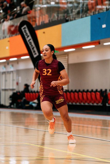 Rotorua number 32 runs up court in a maroon uniform.