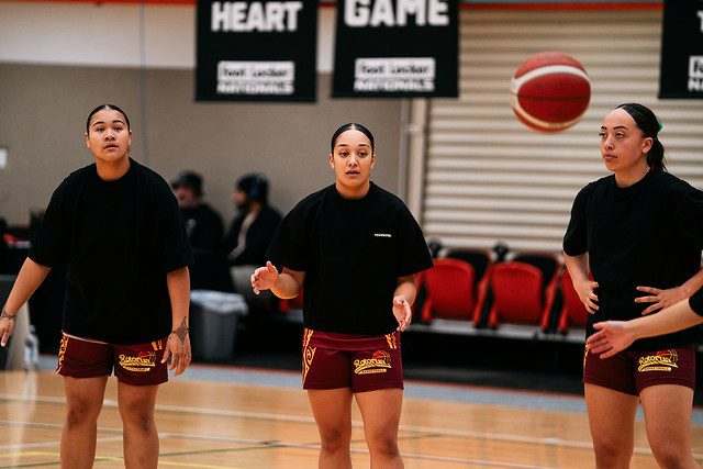 Rotorua players in black warmup shirts track a pass.