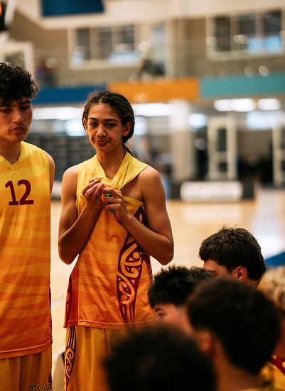 Rotorua players in gold uniforms listen during a team discussion.