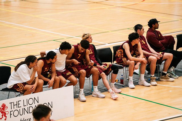 Rotorua players and staff watch the game together from the bench.