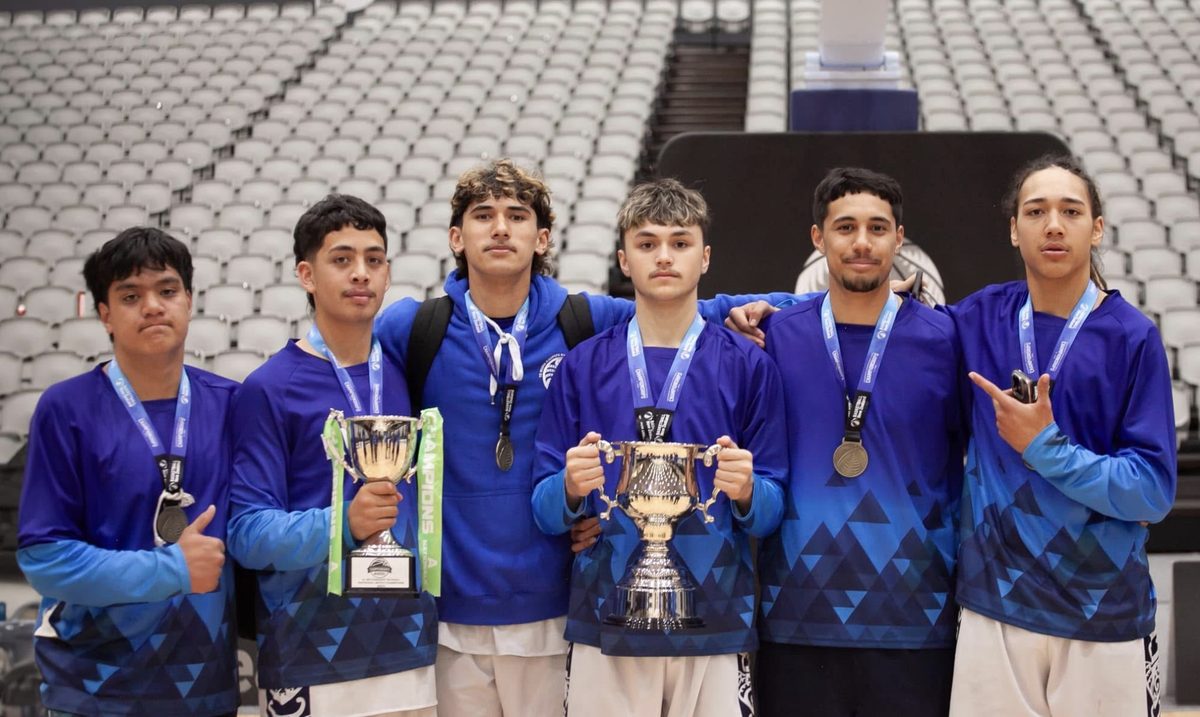 Six Te Kura Kaupapa Māori o Ruamata players wear medals and hold two championship trophies.